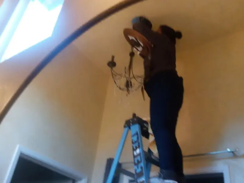 Electrician installing a chandelier in a San Benito residence
